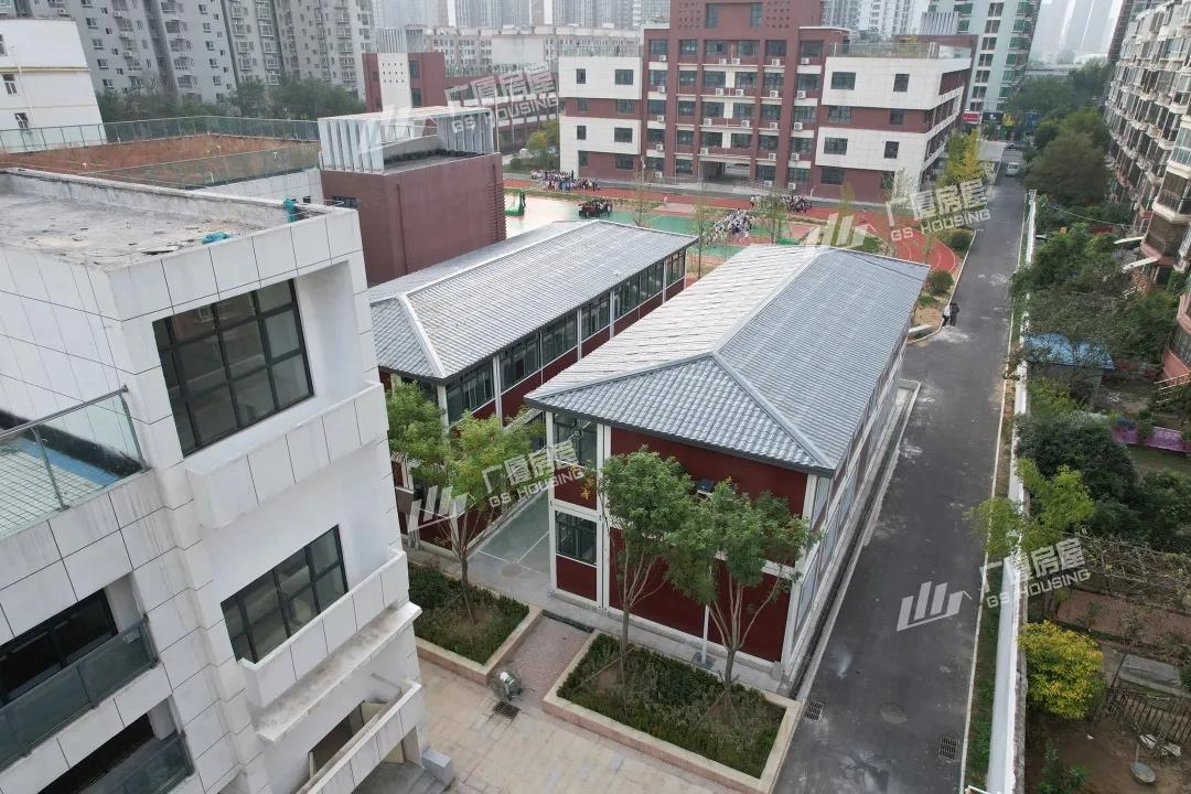 modular classroom building exterior with red facade and urban residential surroundings modular classroom building exterior with red facade and urban residential surroundings