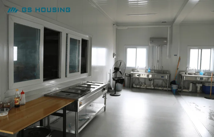 prefab construction camp kitchen and dining area interior with tables and food service counter