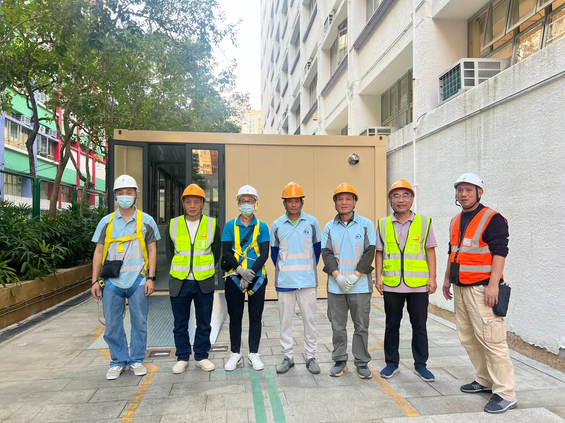 Construction team in safety gear standing in front of completed modular classroom building at Tai Po school, Hong Kong
