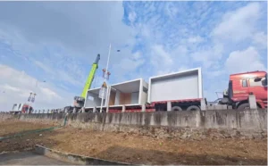 Four modular toilet units delivered to Sucun project site on flatbed truck with crane onsite
