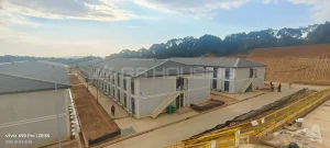 Ground-level view of two-storey modular dormitory buildings with external staircases at the IPIP mining camp in Indonesia