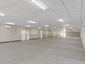 Interior of the EPC site office at the SDW modular construction camp in Saudi Arabia, showing a large open-plan office space with suspended ceiling, LED lighting, finished wall panels, multiple doors, wall-mounted air conditioning units and grey flooring